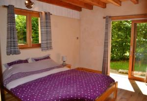 um quarto com uma cama roxa e 2 janelas em Maison de 2 chambres avec piscine partagee jardin clos et wifi a Gembrie em Gembrie