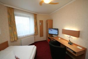 a hotel room with a bed and a desk and a television at Akzent Hotel Oberhausen in Oberhausen