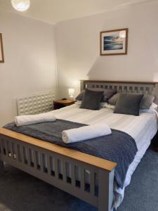 1 dormitorio con 1 cama grande con sábanas y almohadas blancas en Eithin Bach, en Caernarfon