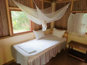 Bett in einem Zimmer mit Fenster in der Unterkunft Onja Surf Camp in Mahambo