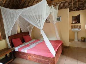 Schlafzimmer mit einem Bett mit Moskitonetz in der Unterkunft Onja Surf Camp in Mahambo