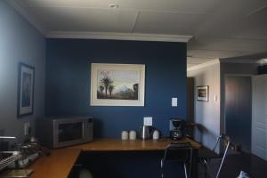 a room with a blue wall with a wooden desk at Aloe Ocean Flatlet in Bettyʼs Bay