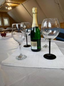 three wine glasses and a bottle on a table at Chata Veverička Oravská Lesná in Oravská Lesná