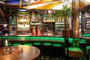 eine Bar mit grünen Hockern und einer Theke mit Alkohol in der Unterkunft Pension Havana Club in Weimar