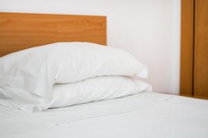a stack of white pillows sitting on top of a bed at Rocha Tower by Beach Rentals in Portimão