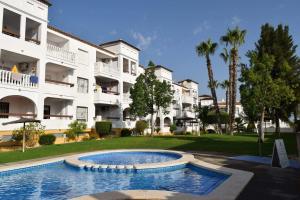 a pool in front of a building with palm trees at FABULOUS 2 BED 2 BATH APARTMENT ! in Villamartin
