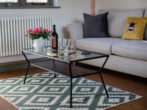 a living room with a glass table and a couch at Paddock Cottage in Winchcombe