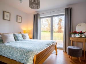a bedroom with a bed and a large window at Paddock Cottage in Winchcombe