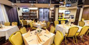 a restaurant with white tables and yellow chairs at Hotel Forum - Free Parking for cars in Sofia