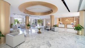 a lobby with white chairs and a large ceiling at Alanda Marbella Hotel in Marbella