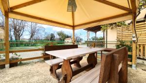 een houten tafel en stoelen onder een paviljoen bij Agriturismo Barbadoro in San Vincenzo