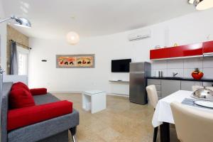 a living room with a red couch and a kitchen at Ark Beach Apartments next to the beach in Stobrec in Split