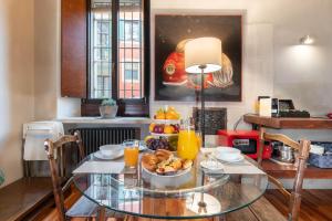 a glass table with a bowl of fruit and orange juice at Il Garbo Apartments and Suite in Verona