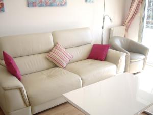 ein Wohnzimmer mit einer weißen Couch mit rosa und lila Kissen in der Unterkunft Appartement d'une chambre a Antibes a 250 m de la plage avec jardin clos et wifi in Antibes
