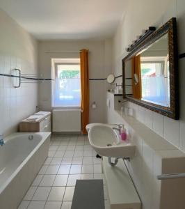 W łazience znajduje się umywalka, wanna i lustro. w obiekcie Rohrbruch w mieście Lansen