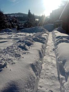 Górski Zakątek z kominkiem i tarasem في Laliki: طريق مغطى بالثلج مع الشمس في الخلفية