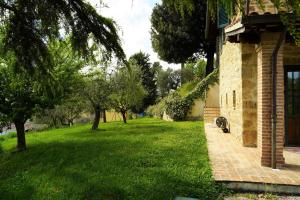 einen grünen Hof neben einem Backsteingebäude mit Bäumen in der Unterkunft Agriturismo Ai Lecci in Ramazzano