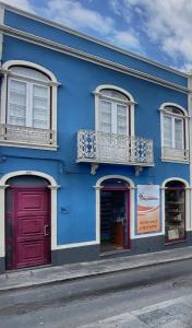 ein blaues Gebäude mit roten Türen auf einer Straße in der Unterkunft Além do Mar Apartment - RRAL n. 3214 in Ribeira Grande