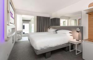 a bedroom with a large white bed and a mirror at YOTEL Edinburgh in Edinburgh