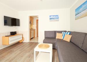 uma sala de estar com um sofá cinzento e uma mesa em Appartement Riterspöör 24 em Westerland