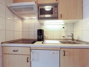 eine kleine Küche mit einer Spüle und einer Mikrowelle in der Unterkunft Appartement Riterspöör 24 in Westerland