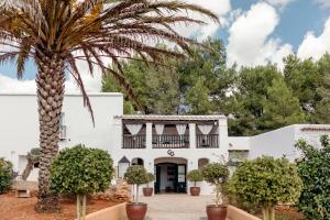ein weißes Haus mit einer Palme davor in der Unterkunft Agroturismo Can Guillem in Santa Gertrudis