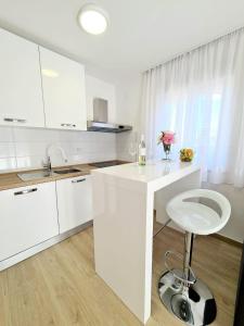 a white kitchen with a white counter and a stool at Apartment Ane 3 in Tisno