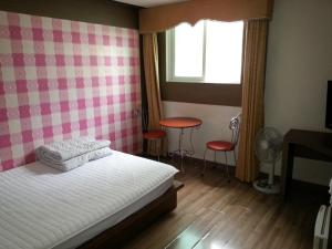 a bedroom with a bed and a window and a table at Egg Motel in Busan