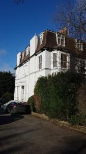 a white house with a car parked in front of it at Lovely 2 Bedroom Flat Wifi Close to the beach in Bournemouth