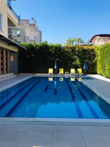 a swimming pool with blue water and yellow chairs at Lemon Hotel in Antalya