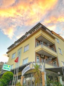 a hotel with a yellow building with a sunset at Lemon Hotel in Antalya