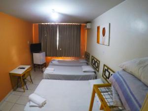 Habitación con 4 camas, mesa y TV. en Hotel Itaipu, en Goiânia