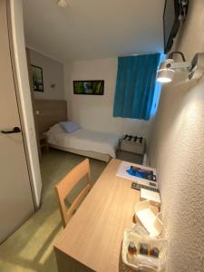 a small room with a table and a bed at HOTEL RESTAURANT OLYMPE in Aix-en-Provence