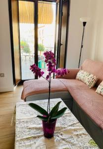 セビリアにあるApartamento céntricoのリビングルーム(テーブルの上に紫の花を飾った花瓶付)