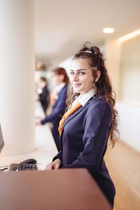 une femme assise à un bureau avec les bras croisés dans l'établissement Spa Resort Geinberg, à Geinberg