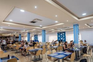 a cafeteria with tables and people sitting at tables at Hotel Festa Brava by ALEGRIA in Lloret de Mar