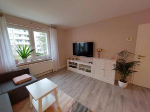 ein Wohnzimmer mit einem Flachbild-TV auf einem weißen Schrank in der Unterkunft Helles modern eingerichtetes Apartment in Halle an der Saale