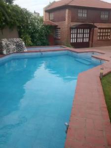 una gran piscina azul frente a una casa en Duplex El Duende en Olavarría