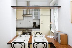 eine Küche mit einem Tisch und Stühlen sowie eine Küche mit einem Herd in der Unterkunft Ferienwohnung Bregenz 6 top 3 in Bregenz
