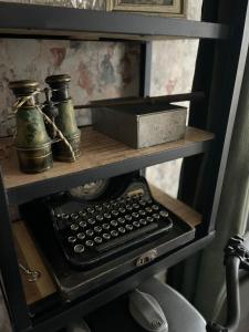 une étagère avec une machine à écrire et une boîte sur elle dans l'établissement Le rétro, à Verdun-sur-Meuse