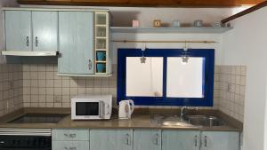 オルソラにあるTranquilo y Acogedor Apartamentoのキッチン(青いキャビネット、シンク、電子レンジ付)