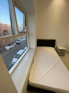 a bed in a room with a large window at Economic rooms for rent in Dubai in Dubai