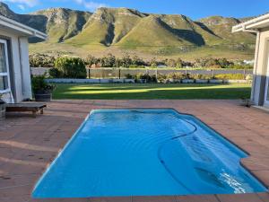 a blue swimming pool with a mountain in the background at Bird's View in Hermanus