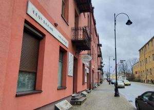 ピョートルクフ・トルィブナルスキにあるCosy Roomsの車が停まった街路の赤い建物