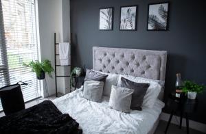 a bedroom with a white bed with four pictures on the wall at Modern city centre apartment roof garden in Manchester