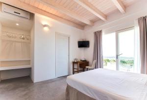 a white bedroom with a bed and a window at Alghero Villa Carrabufas villa con piscina vista mare per 10 persone in Valverde