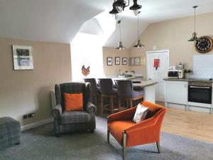 a living room with chairs and a kitchen at The Courtyard Apartment at Cefn Tilla Court, Usk in Usk