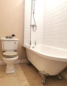 a bathroom with a white tub and a toilet at The Courtyard Apartment at Cefn Tilla Court, Usk in Usk