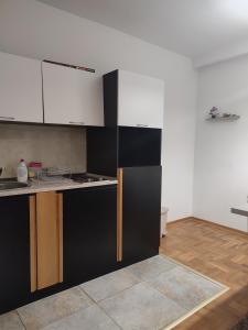 a kitchen with black and white cabinets and wooden floors at Zlatiborski Konaci-Apartman Maletic in Zlatibor