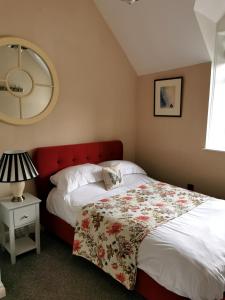 1 dormitorio con 1 cama grande y cabecero rojo en The Courtyard Apartment at Cefn Tilla Court, Usk en Usk